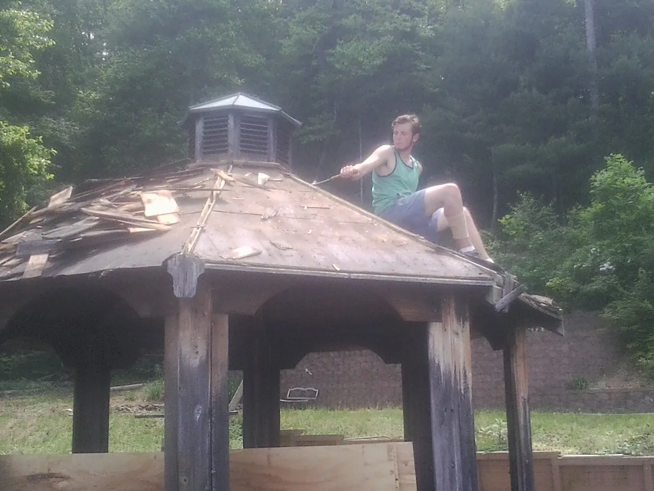 Tearing the old roof off a wooden gazebo before new shakes in Peak