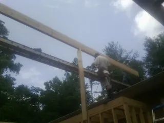 Carpenter setting a ridge beam over a new addition frame — Ice Dam Removal by Roofing Brothers in Peak