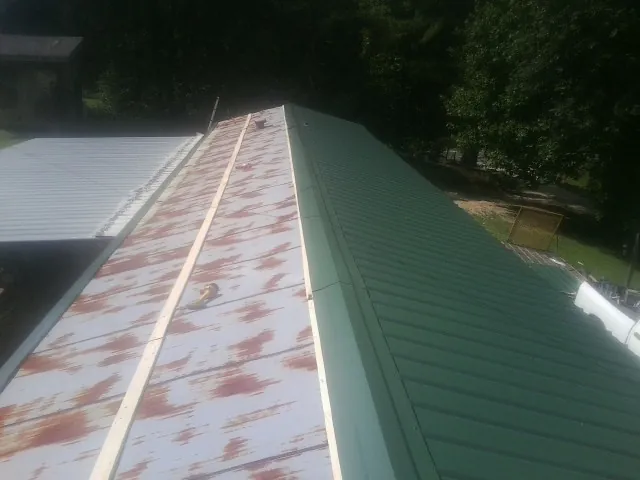 Old rusted panels beside newly installed green metal roofing — Wind Damage Roof Repair by Roofing Brothers in Peak