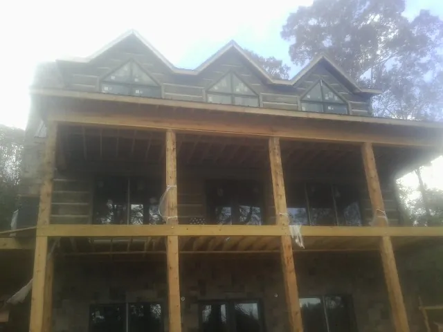 Dormers and porch framing on a large log home under construction — Roof Coating work by our crew in Peak