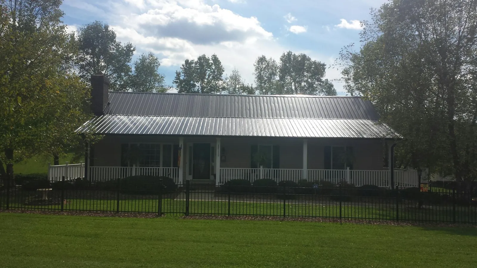 Gray metal roof on a brick ranch with a full width front porch — Gutter Guard Installation work by our crew in Peak