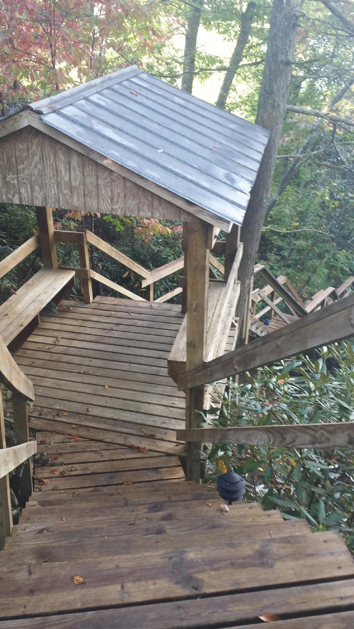 Metal roofed shelter over wooden steps on a wooded walkway — Skylight Repair & Installation work by our crew in Peak