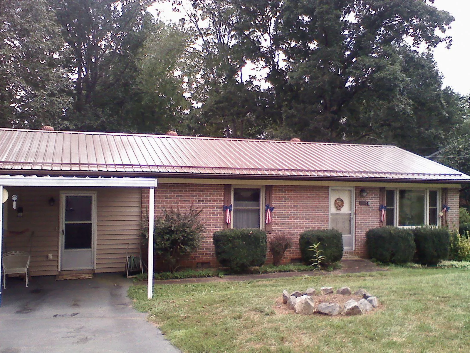 Bronze metal roof and carport on a brick ranch home — Roof Repair work by our crew in Peak